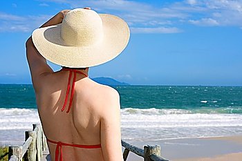 Woman with hat looking at the sea