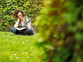 young woman reading book in park