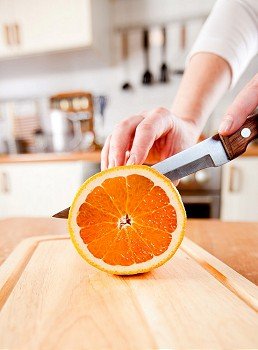 Woman´s hands cutting fresh orange on kitchen