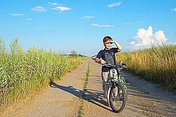 The boy with a bicycle on long road 