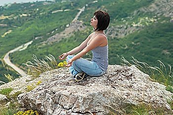 Woman in meditation, relaxing on the rock