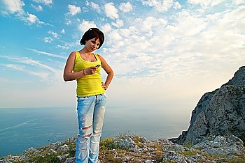 Young woman with mobile phone on cloudscape background
