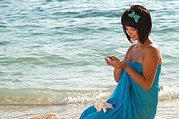 Young woman on the beach with stones in hands