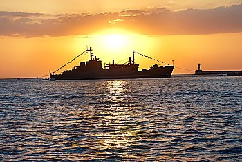 Military ship against beautiful red marine sunset
