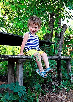 happy baby sitting on wooden bench in garden
