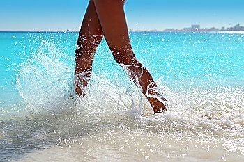 Woman legs walking splashing beach water in Caribbean turquoise sea