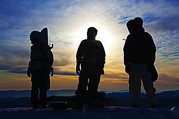 Silhouettes of the three backcountry freeriders in evening (Dragobrat ski resort, Ukraine).