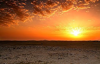 Sunset over the rocky Qatari desert, south of Doha, with sand dunes in the distance