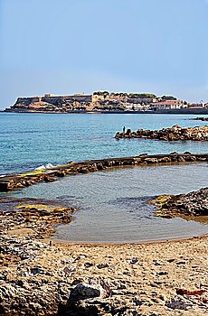 A view of the Fortezza castle in its promontory at the heart of Rethymnon city, Crete, seen from a small cove used used by swimmers a mile or so to the west.