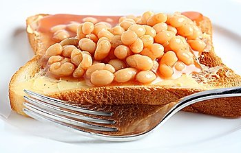 Extreme close-up on a plate of beans on toast with a fork.