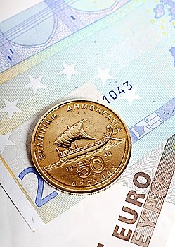 A fifty drachma coin lying on euro notes which replaced the Greek currency. Greece´s economic woes are now seen as a threat to the stability of the euro.