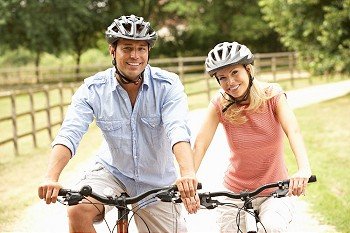 Couple Cycling In Countryside Wearing Safety Helmets