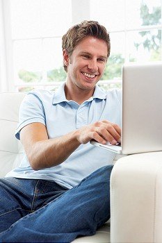Man Sitting On Sofa Using Laptop At Home