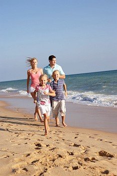 Portrait Of Running Family On Beach Holiday
