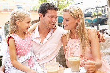 Young Family Enjoying Cup Of Coffee In CafZ Together