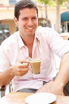Young Man Enjoying Cup Of Coffee In CafZ