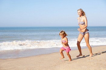 Mother chasing young girl on beach