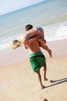 Young couple play on beach
