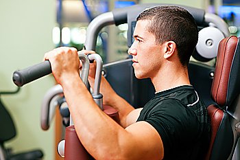 Man doing fitness training on a butterfly machine with weights in a gym