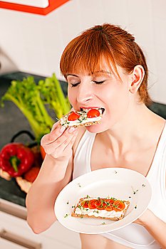 Woman eating healthy in her diet, having a crispbread with cream cheese, cress, and tomatoes
