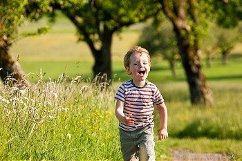 Little boy running down a dirtpath in a beautiful landscape in summer, very light and happy scene