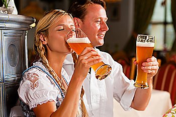 Couple in Bavarian Tracht drinking wheat beer in a typical pub