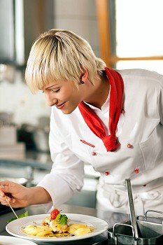 Female Chef in a restaurant or hotel kitchen cooking delicious food, both are finishing the dishes
