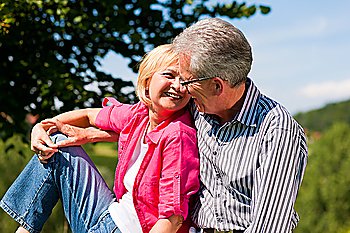 Visibly happy mature or senior couple outdoors arm in arm deeply in love 