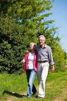 Visibly happy mature or senior couple outdoors arm in arm having a walk 