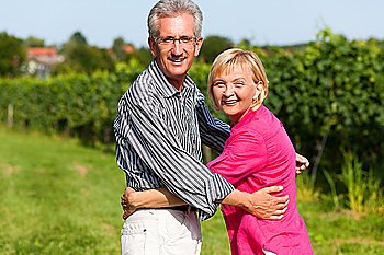 Visibly happy mature or senior couple outdoors arm in arm having a walk 