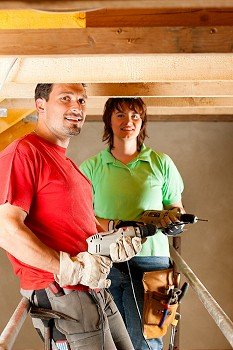 DIY couple in home improvement with hand drill standing on a scaffold