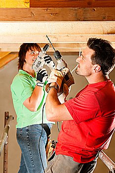 DIY couple in home improvement with hand drill standing on a scaffold