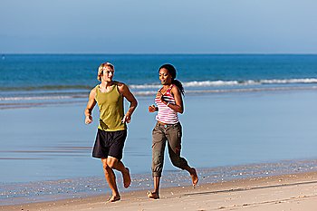 Young sport couple - Caucasian man and African-American woman - jogging on the beach