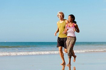 Young sport couple - Caucasian man and African-American woman - jogging on the beach