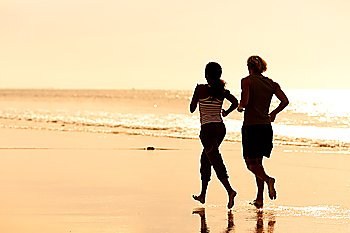 Young sport couple - jogging on the beach in sunset
