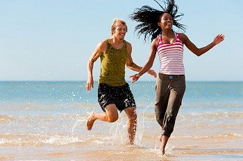 Young sport couple - Caucasian man and African-American woman - jogging on the beach in a playful mode