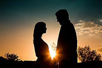 Couple in love touching each other backlit in a sunset in summer