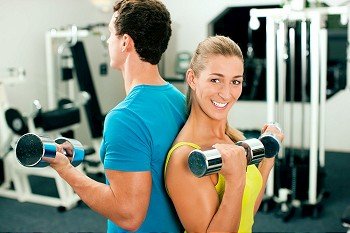 couple in the gym, rivaling each other, exercising with dumbbells 