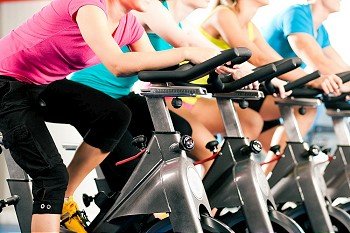 Group of four people spinning in the gym, exercising their legs doing cardio training