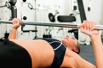 Woman in gym exercising for better fitness with a barbell