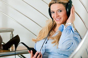 Business woman listening music at home sitting relaxed on the stairs