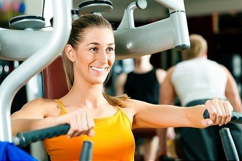Woman doing fitness training on a butterfly machine with weights in gym or fitness 
