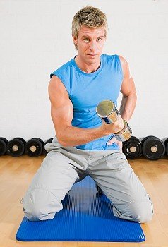 Young sportive man working out using dumbbells in the gym