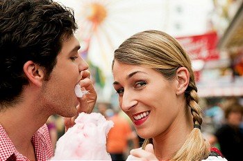 Young couple in traditional German costume on a fair like the Oktoberfest, with cotton candy