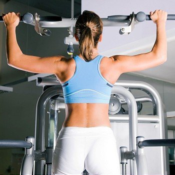 Beautiful woman doing pull-ups on a machine in the gym