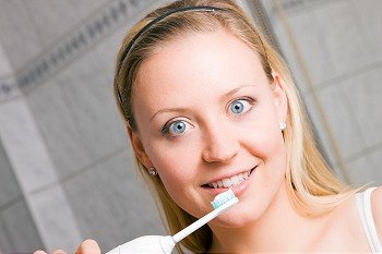 Young woman brushing her teeth with an electrical toothbrush