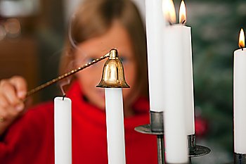 Child extinguishing Christmas candles in front of a Christmas tree