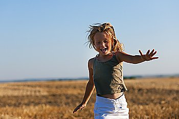Girl child running over a harvested field on a beautiful fall day