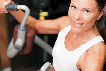 Woman doing fitness training on a leg extension push machine with weights in a gym