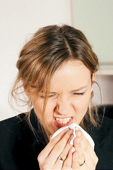 Woman with a flu or an allergy sneezing into her handkerchief